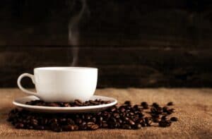 Best Coffee Maker with Grinder, photo of a white coffee mug sitting on whole coffee beans