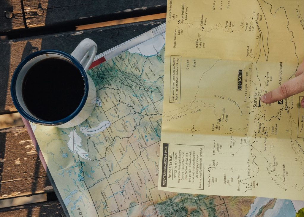 makita coffee maker, photo of black coffee sitting on top of two maps on a wooden table