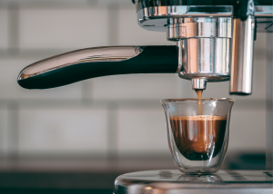 breville duo temp pro. photo of an espresso shot sitting under an espresso machine just being made